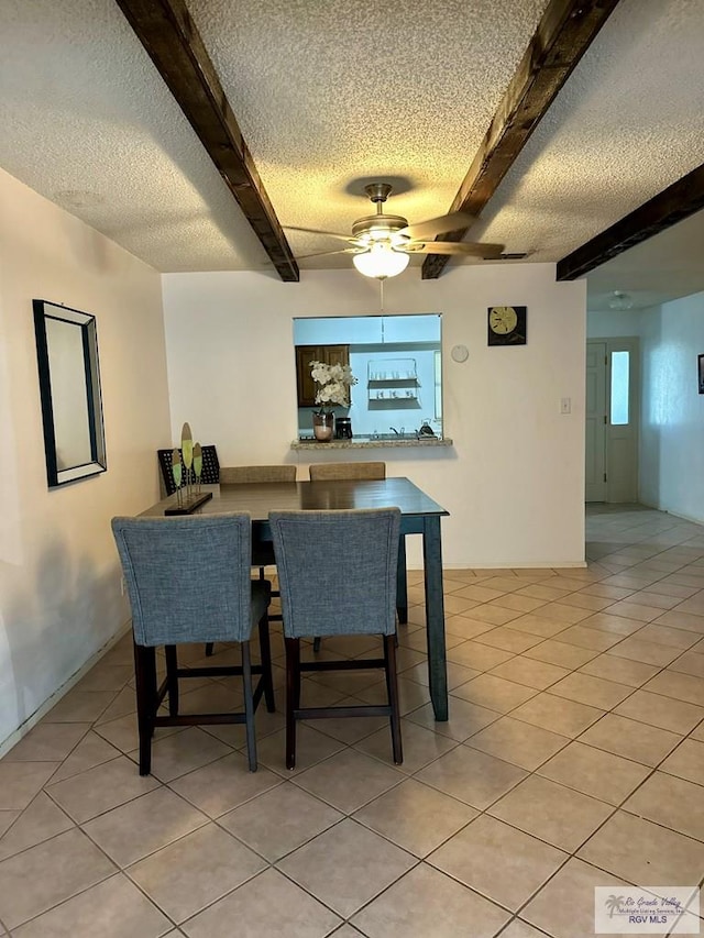 tiled dining room featuring beam ceiling, ceiling fan, and a textured ceiling