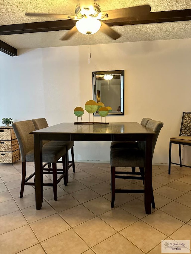 dining space featuring beam ceiling, a textured ceiling, ceiling fan, and light tile patterned flooring