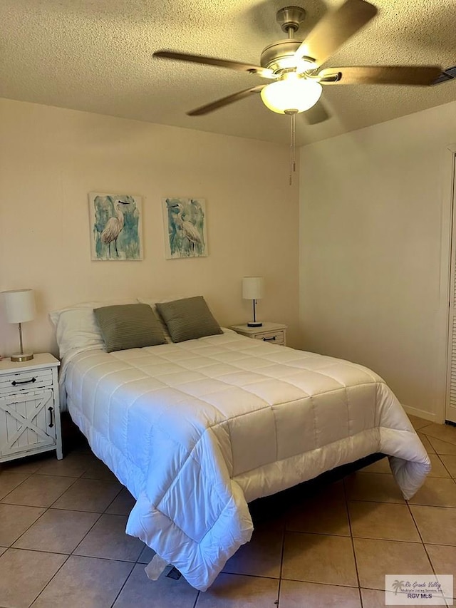 tiled bedroom with ceiling fan and a textured ceiling