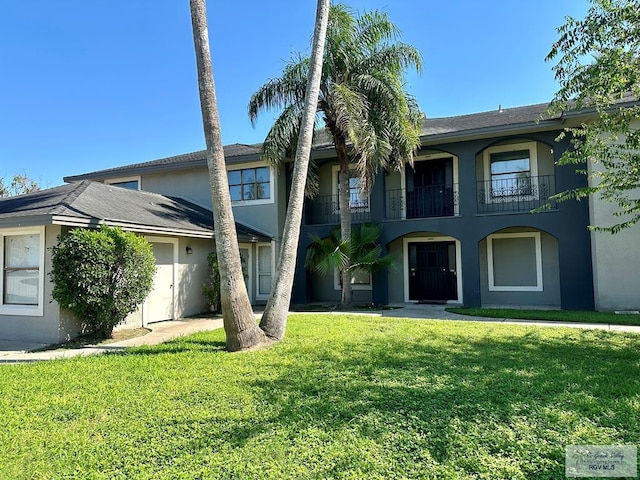 view of property with a balcony and a front lawn