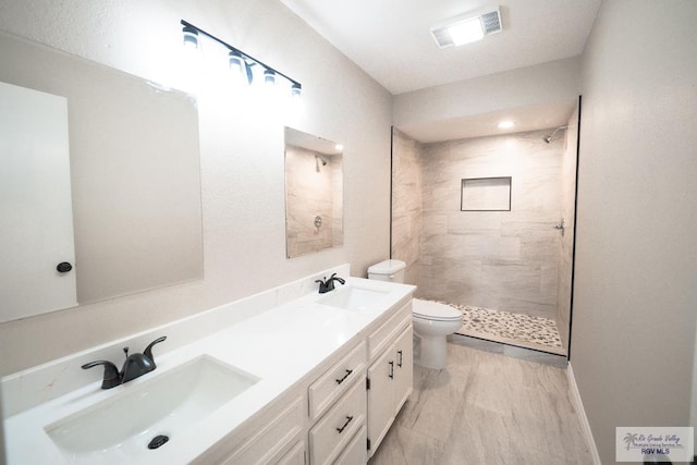 full bathroom featuring a sink, visible vents, toilet, and tiled shower