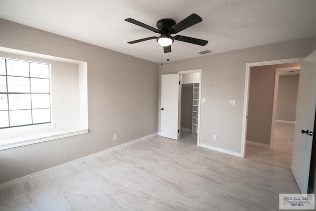 unfurnished bedroom featuring ceiling fan, baseboards, a spacious closet, and visible vents