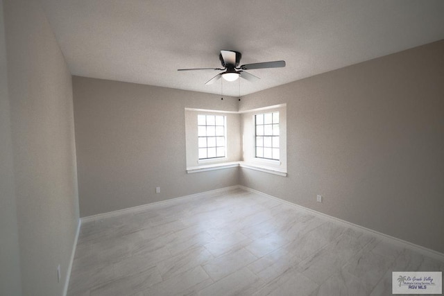 spare room featuring ceiling fan and baseboards