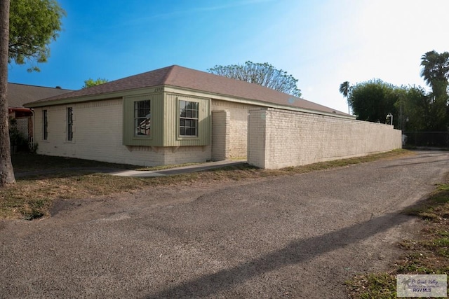 view of home's exterior with brick siding and fence