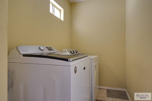 laundry area featuring laundry area, baseboards, washing machine and clothes dryer, and light tile patterned floors