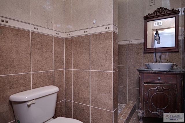 bathroom featuring tile walls, visible vents, vanity, and toilet