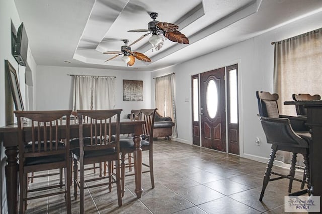 dining room featuring baseboards and a tray ceiling