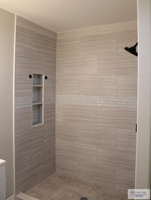 bathroom with a tile shower and vanity