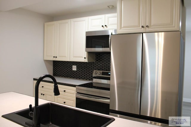 kitchen featuring tasteful backsplash, white cabinetry, sink, and appliances with stainless steel finishes