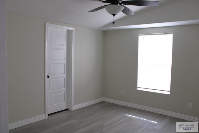 empty room featuring light hardwood / wood-style floors, vaulted ceiling, and ceiling fan