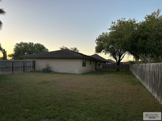 yard at dusk featuring central AC unit