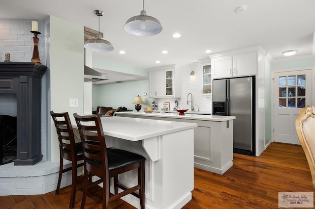 kitchen featuring white cabinets, stainless steel fridge, decorative backsplash, and dark wood-type flooring