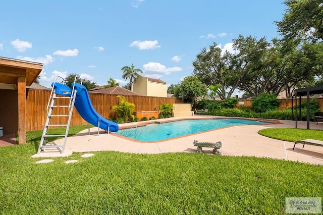 view of swimming pool featuring a lawn, a patio area, and a water slide