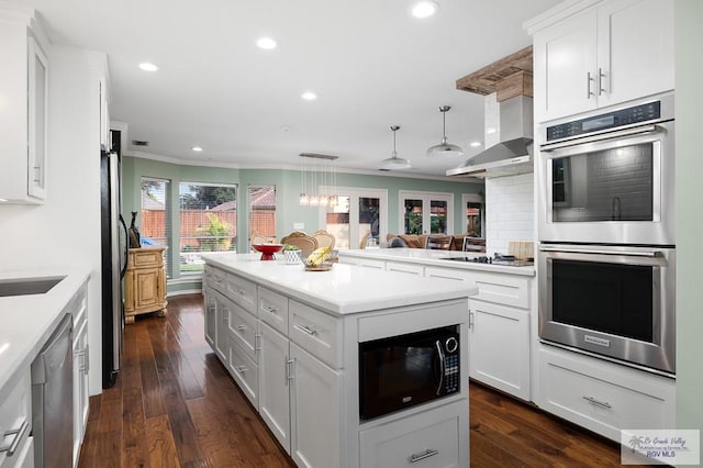 kitchen featuring dark wood-type flooring, black appliances, white cabinets, decorative light fixtures, and extractor fan