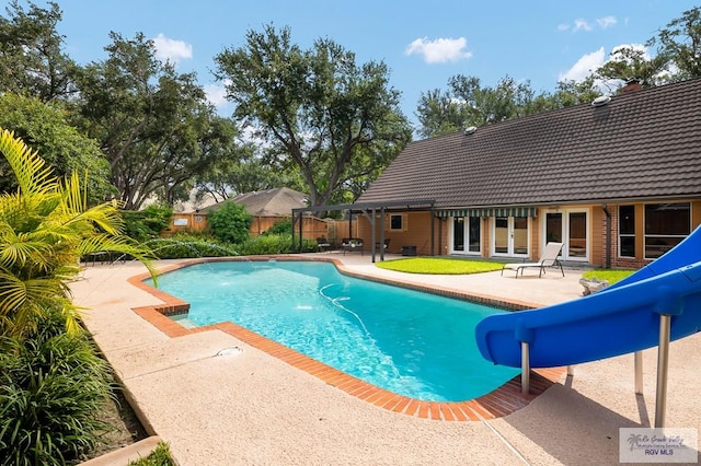 view of swimming pool with french doors, a water slide, and a patio