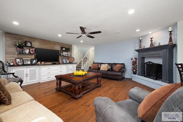 living room with ceiling fan, wood walls, and wood-type flooring