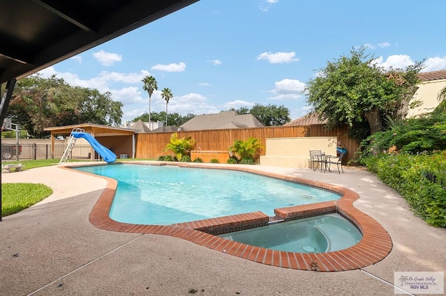 view of pool featuring an in ground hot tub, a water slide, and a patio