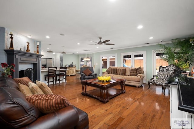 living room with french doors, ornamental molding, ceiling fan, a fireplace, and hardwood / wood-style floors