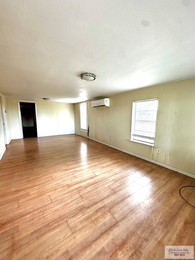 unfurnished living room with a wall mounted air conditioner and light wood-type flooring