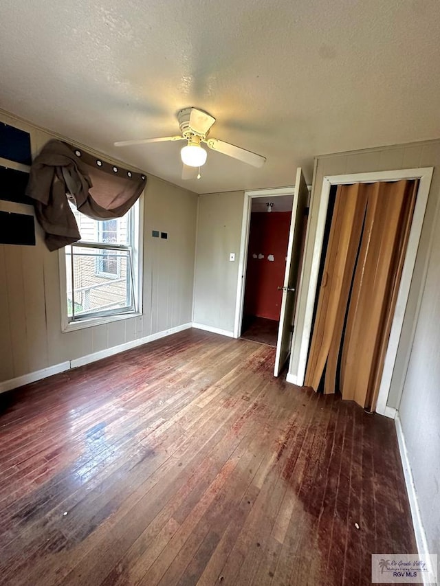 unfurnished bedroom featuring a textured ceiling, ceiling fan, a closet, and dark hardwood / wood-style floors