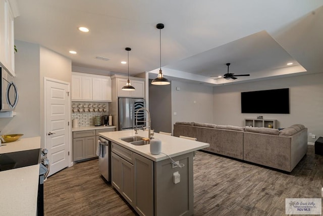 kitchen featuring a kitchen island with sink, hanging light fixtures, ceiling fan, appliances with stainless steel finishes, and dark hardwood / wood-style flooring