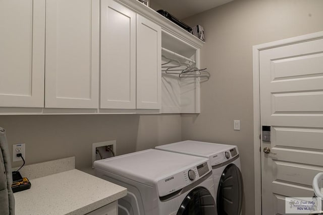 clothes washing area featuring washing machine and clothes dryer and cabinets