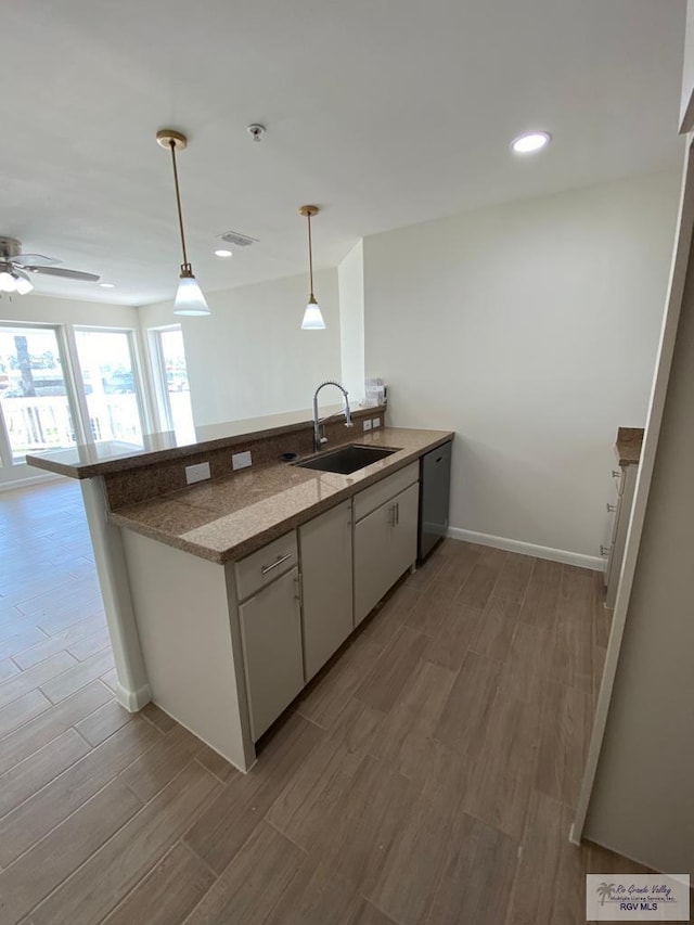 kitchen featuring kitchen peninsula, light hardwood / wood-style floors, hanging light fixtures, and sink