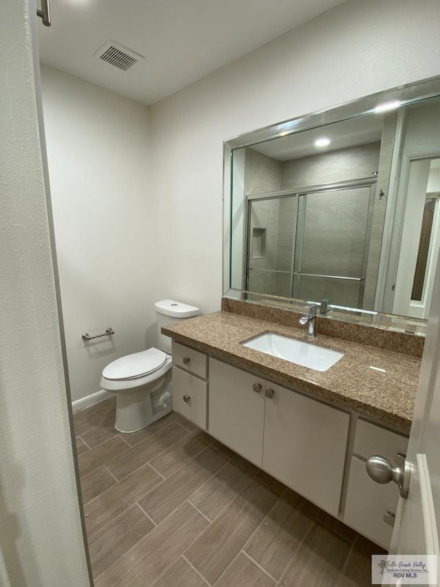 bathroom featuring toilet, vanity, and walk in shower