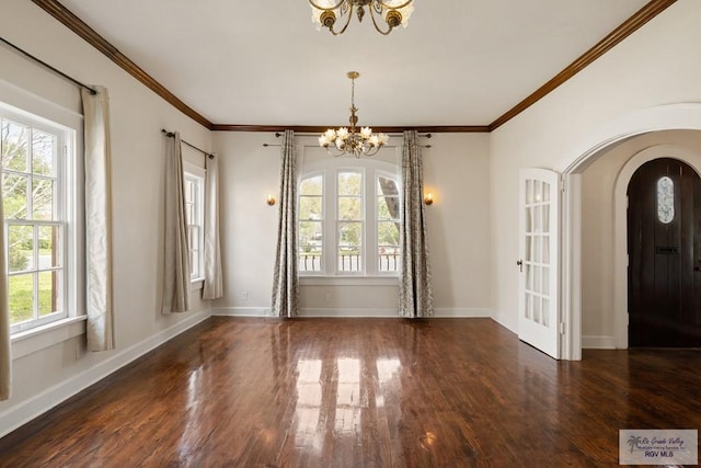 interior space with wood finished floors, arched walkways, a chandelier, and ornamental molding