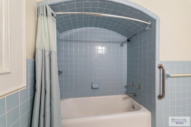 full bath with a wainscoted wall, shower / tub combo with curtain, and tile walls