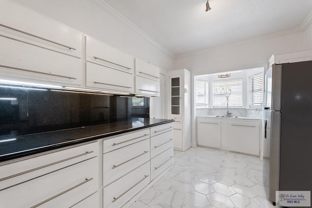 kitchen featuring freestanding refrigerator, ornamental molding, white cabinets, marble finish floor, and tasteful backsplash