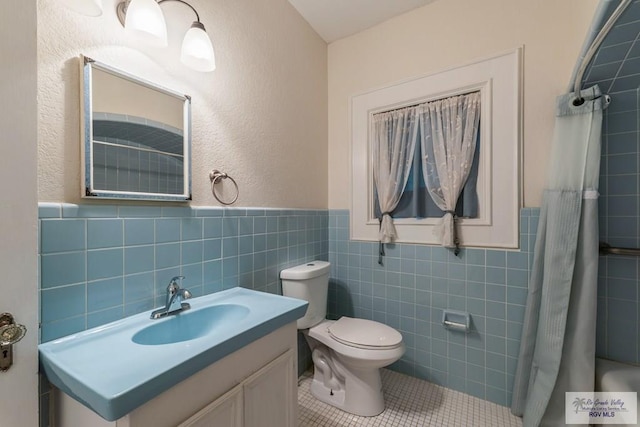 full bathroom with vanity, wainscoting, tile patterned floors, toilet, and tile walls