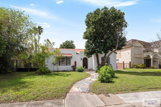 mediterranean / spanish-style home featuring a tile roof, a front lawn, and stucco siding