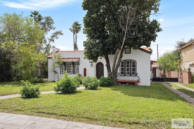 mediterranean / spanish-style home with a front yard, fence, and stucco siding