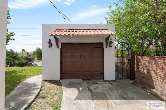 garage featuring a gate, driveway, and fence