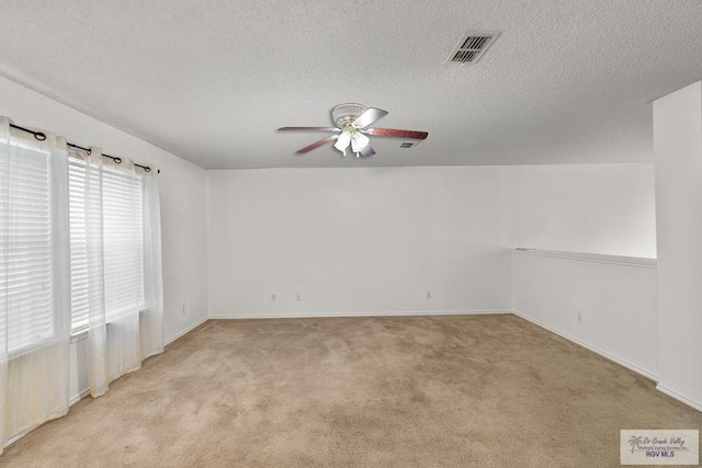 spare room with a textured ceiling, ceiling fan, and light carpet