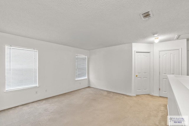 carpeted spare room with a textured ceiling