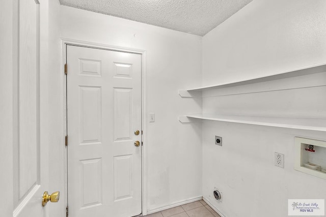 clothes washing area with hookup for an electric dryer, light tile patterned floors, a textured ceiling, and washer hookup