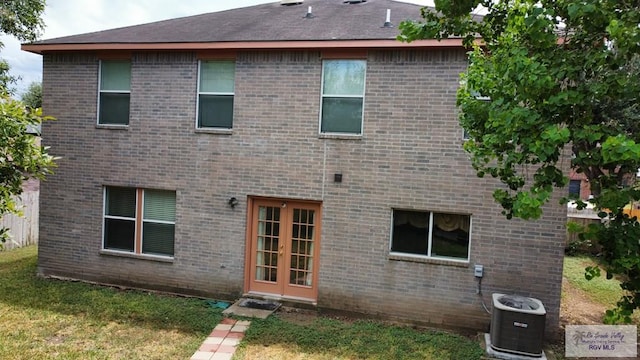 back of property featuring central air condition unit and a yard