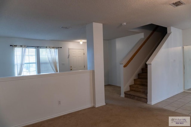 interior space featuring light colored carpet and a textured ceiling