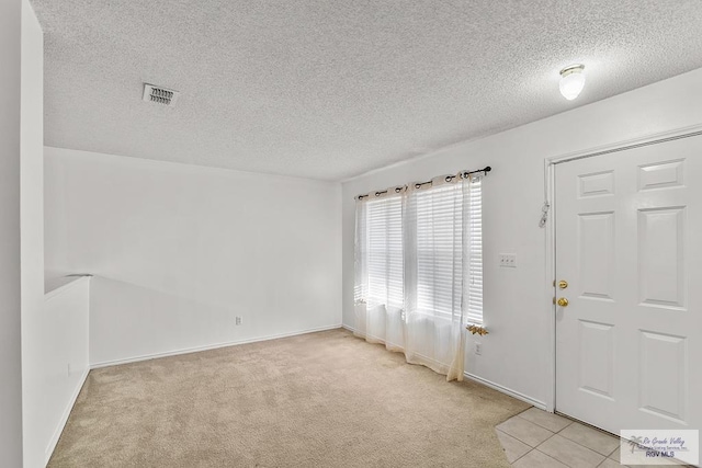 entryway featuring a textured ceiling and light colored carpet