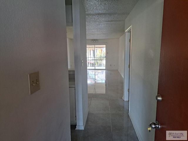 hall featuring dark tile patterned flooring and a textured ceiling