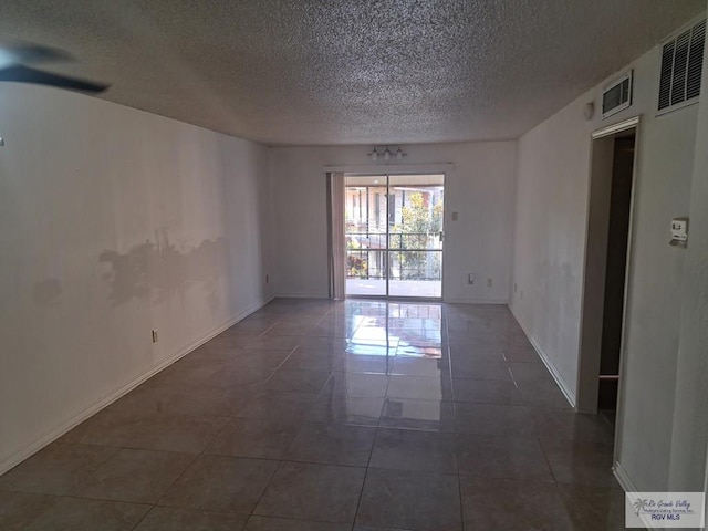 empty room featuring a textured ceiling and dark tile patterned flooring