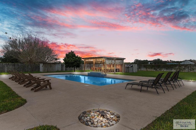 pool at dusk with exterior bar and a patio