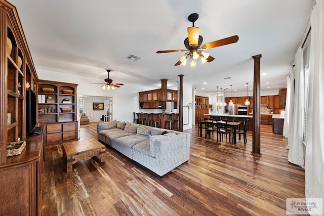 living room featuring ornate columns, ceiling fan, and dark wood-type flooring