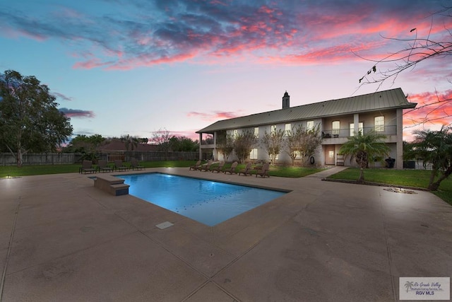 pool at dusk with a yard and a patio