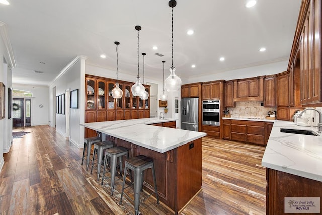 kitchen with sink, decorative light fixtures, tasteful backsplash, a large island, and stainless steel appliances