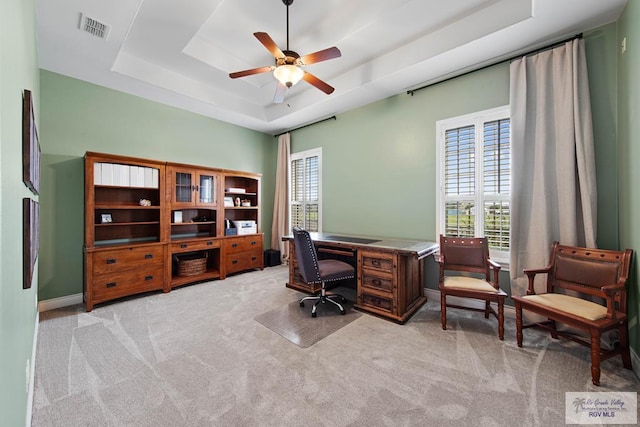 carpeted home office with a raised ceiling and ceiling fan