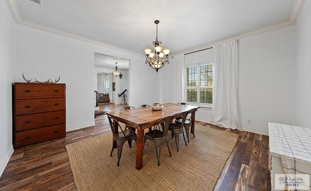 dining room with dark wood-type flooring, crown molding, and an inviting chandelier