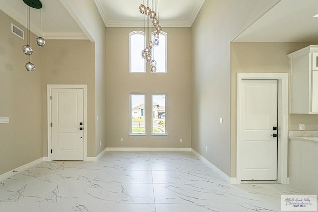 foyer with a towering ceiling, baseboards, visible vents, marble finish floor, and crown molding